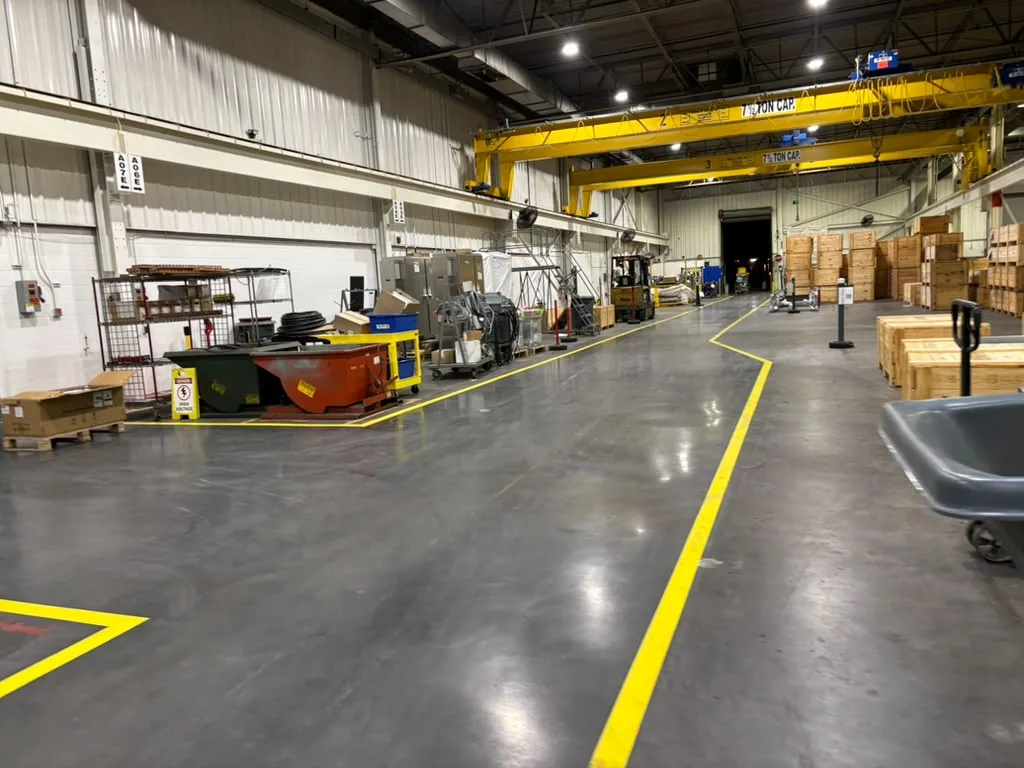 Finished industrial concrete floor with yellow safety lanes and overhead cranes